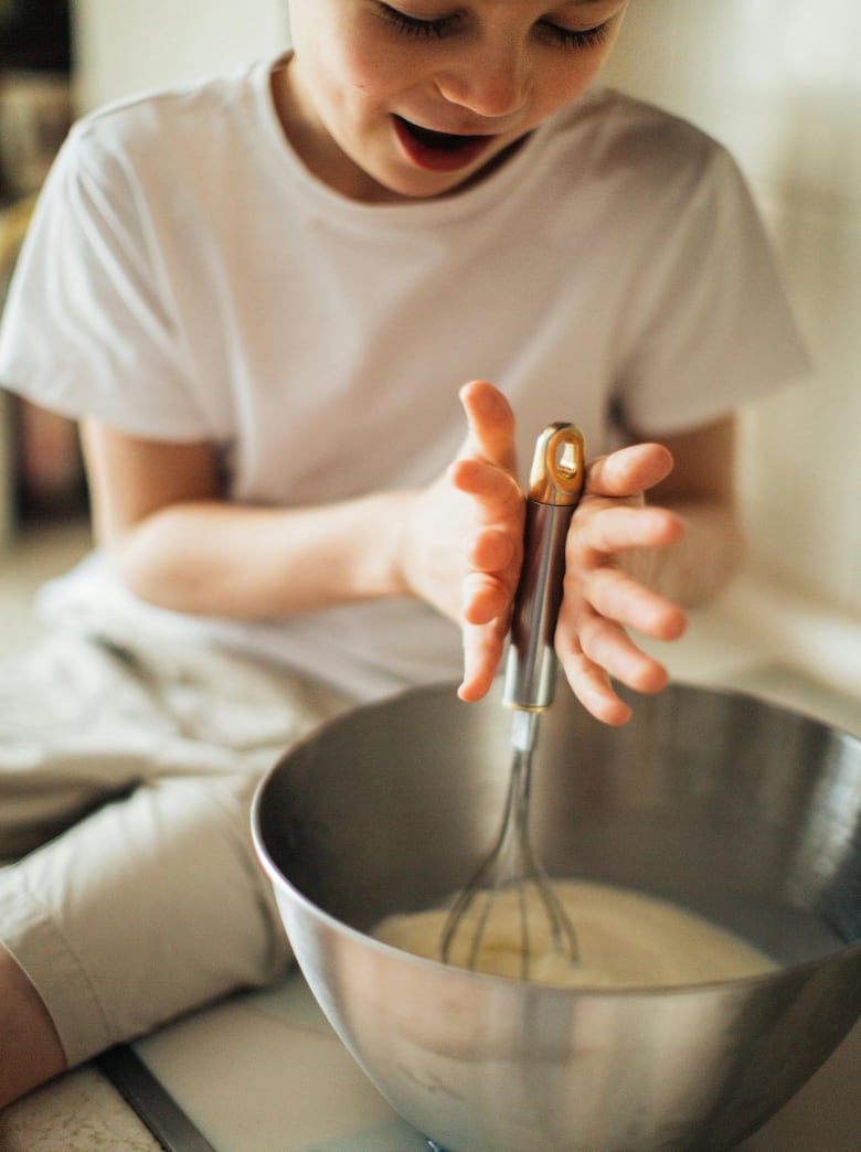 Child whisking batter in a steel bowl during a hands-on family cooking class