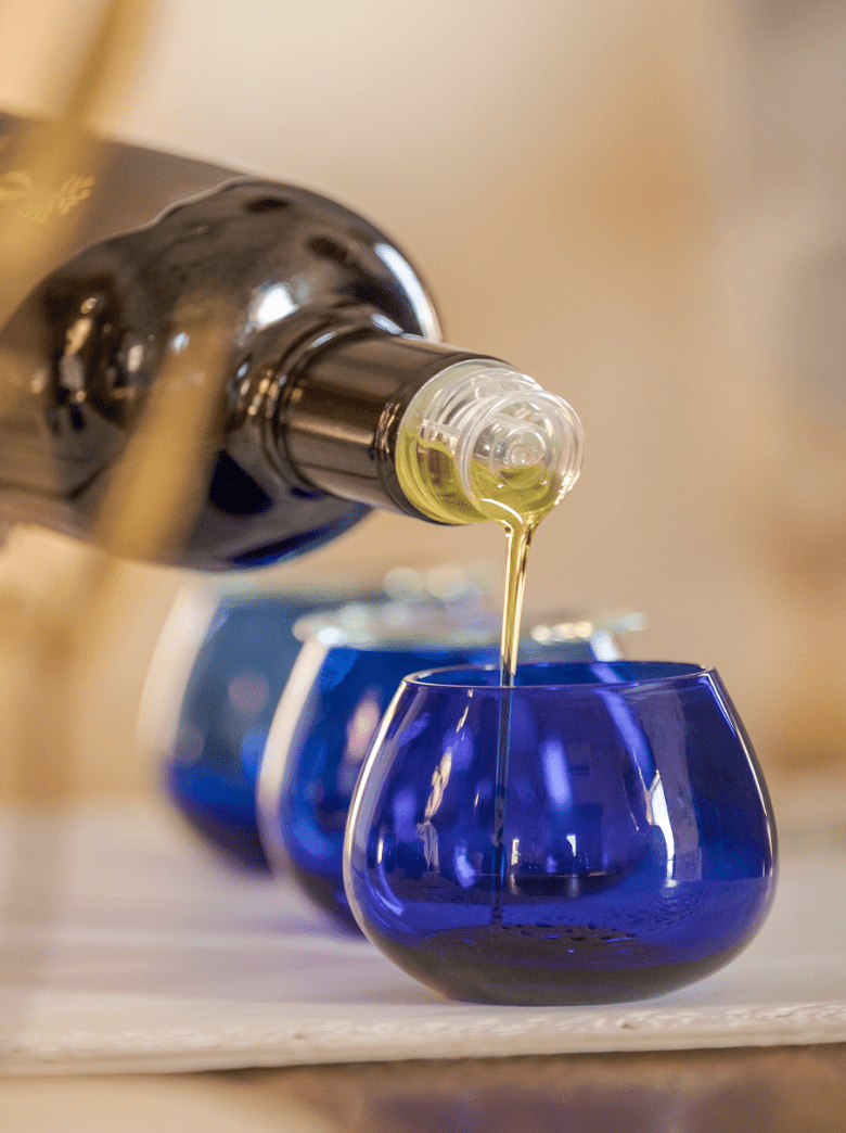 Extra virgin olive oil being poured into tasting glasses during an olive oil tasting experience