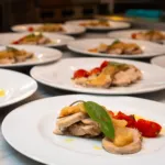 Roastbeef a fette con composta di mele, salvia e pomodorini, un tavolo di piatti per un evento catering