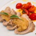Close-up of roast with apple compote, sage and cherry tomatoes seasoned with oil