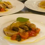 Table of dishes with roast, apple compote and cherry tomatoes for a catered event