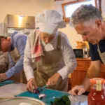 Chef che dimostra la tecnica di taglio delle cipolle ai partecipanti al corso di cucina in Toscana