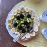 Breakfast plate with sliced ​​banana, blackberries and kiwi arranged in a crown