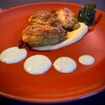 Fried and breaded courgette flowers with cream and basil leaves