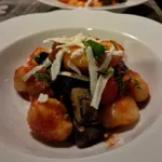 Gnocchi with mushrooms, tomato sauce and cheese flakes