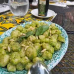 Gnocchi con pesto di basilico e pinoli serviti all'aperto durante un corso di cucina del Chianti