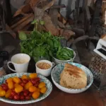 Basilico fresco, pinoli e pane disposti per una lezione di pesto vicino al camino