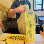 Tagliare un foglio di pasta pressato alle erbe in tagliatelle durante un corso pratico di pasta