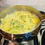 Pasta pappardelle alle erbe che bolle in una pentola sul fornello durante una lezione di cucina