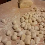 Modellare gnocchi fatti in casa con pasta di patate su una tavola di legno